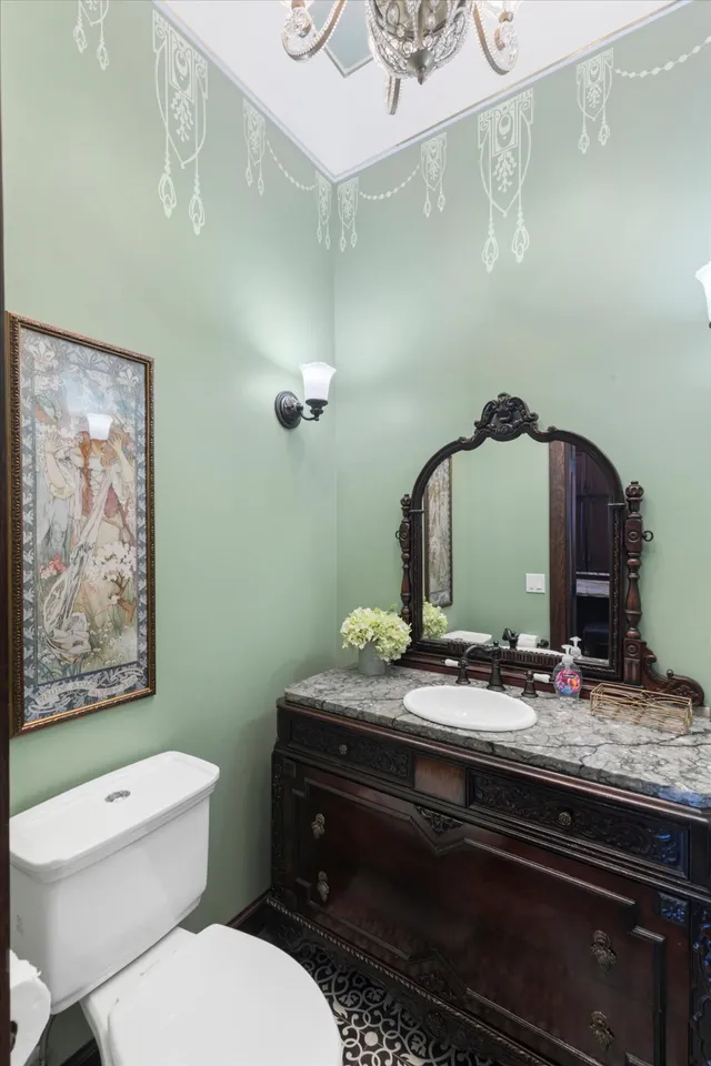 Powder room with sage green walls, chandelier and antique vanity